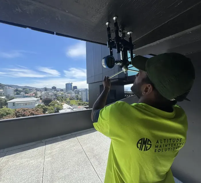 Technician working on roof access equipment above a Wellington building