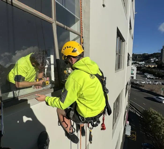 Technician working at a window on an exterior building elevation