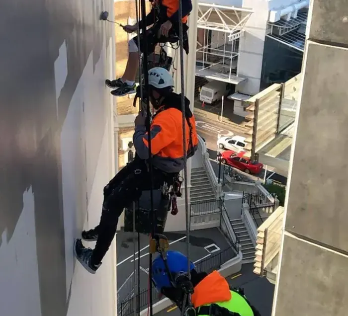 Rope access technician painting an exterior building elevation